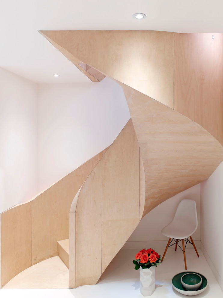 Mid-sized contemporary wood spiral staircase in London with wood risers and wood railing.