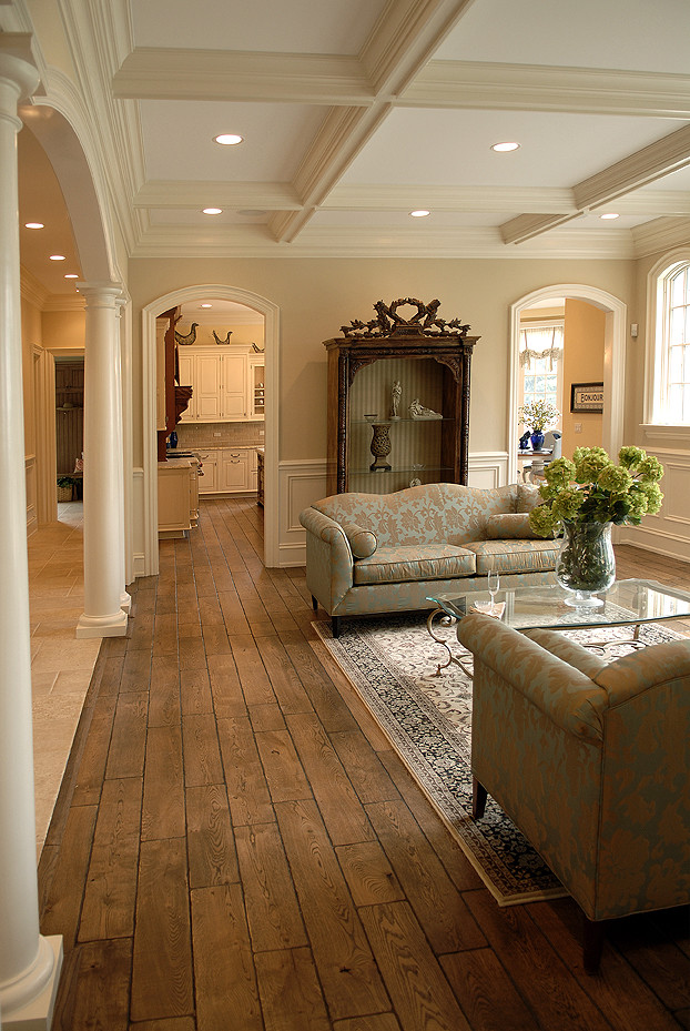 Exemple d'un grand salon avec un sol en bois brun, une cheminée standard, un manteau de cheminée en pierre, un sol marron et un plafond à caissons.