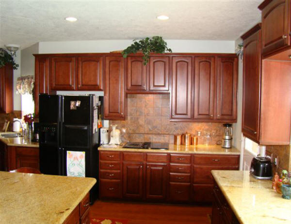 Eat-in kitchen - large transitional u-shaped medium tone wood floor and brown floor eat-in kitchen idea in Houston with a double-bowl sink, raised-panel cabinets, granite countertops, brown backsplash, ceramic backsplash, black appliances, an island and medium tone wood cabinets