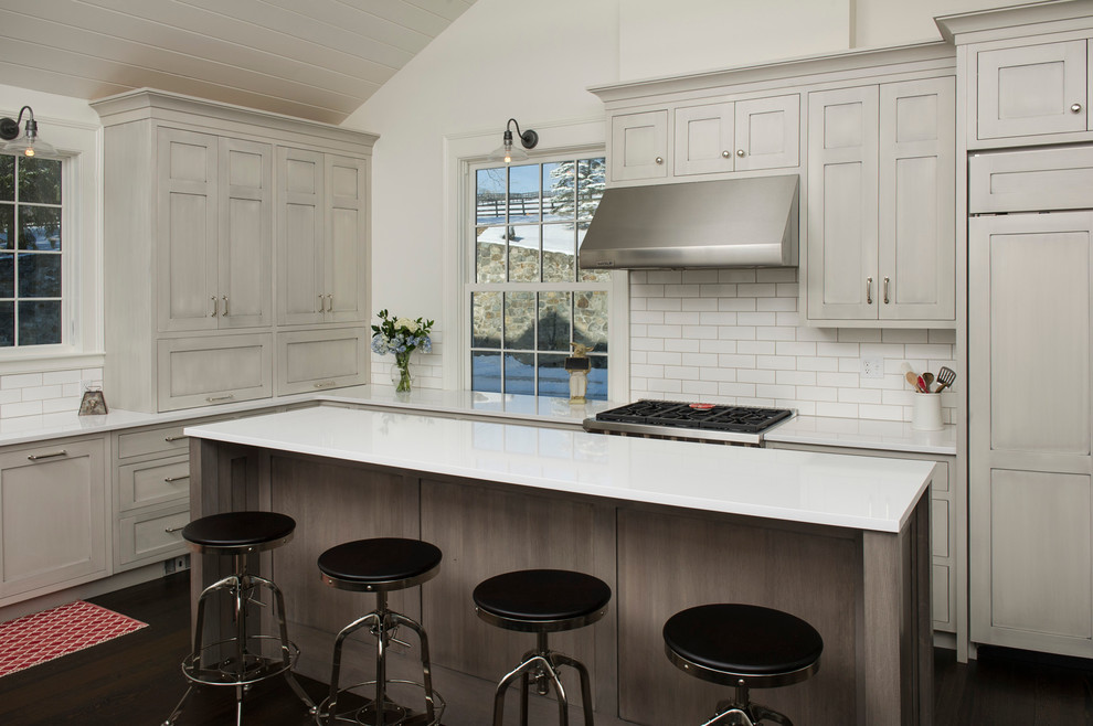 Eat-in kitchen - mid-sized transitional l-shaped dark wood floor eat-in kitchen idea in New York with an undermount sink, shaker cabinets, gray cabinets, quartz countertops, white backsplash, ceramic backsplash, paneled appliances and an island