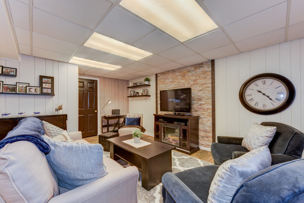 This is an example of a mid-sized transitional fully buried basement in Philadelphia with beige walls, vinyl floors, a standard fireplace and a stone fireplace surround.