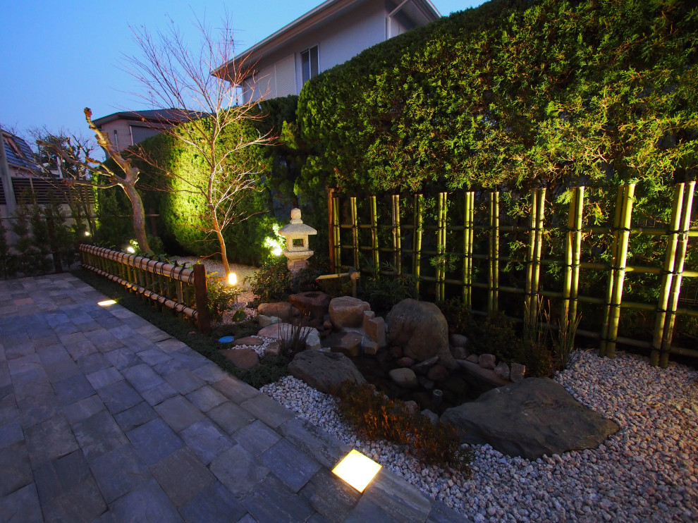 This is an example of a mid-sized asian rock and full sun front yard stone and wood fence formal garden in Tokyo.