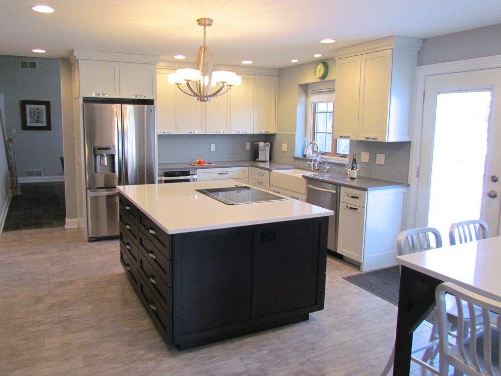Transitional l-shaped porcelain tile eat-in kitchen photo in Chicago with a farmhouse sink, shaker cabinets, white cabinets, quartz countertops, blue backsplash, glass tile backsplash, stainless steel appliances and an island