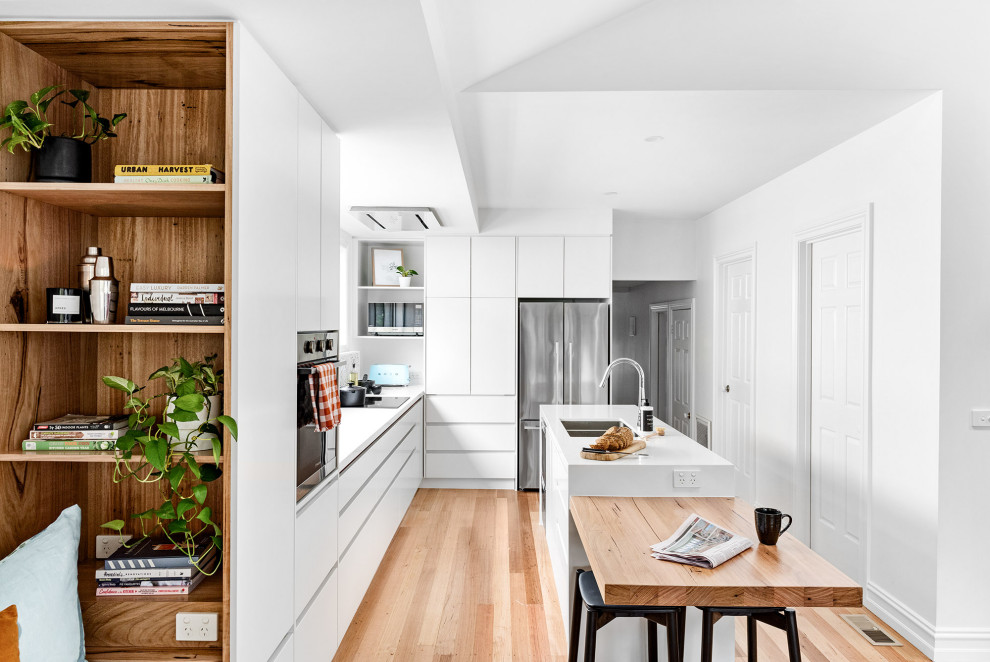 На фото: параллельная кухня-гостиная среднего размера в стиле модернизм с двойной мойкой, белыми фасадами, белым фартуком, техникой из нержавеющей стали, двумя и более островами, желтой столешницей и сводчатым потолком
