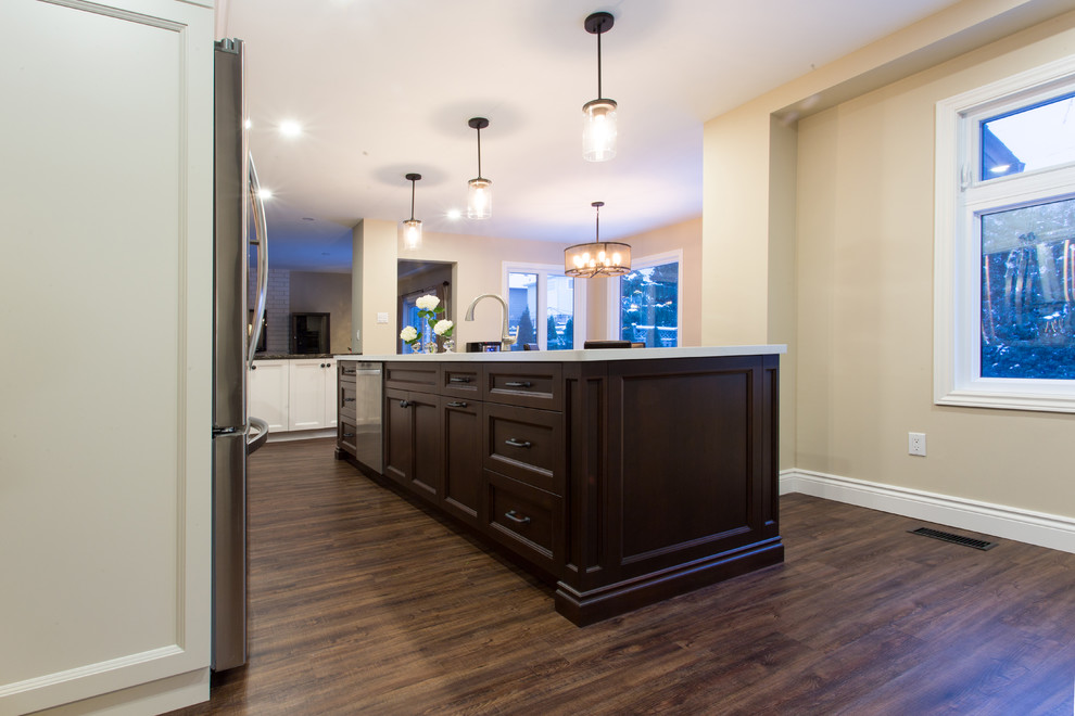 Inspiration for a large transitional l-shaped dark wood floor eat-in kitchen remodel in Orange County with a double-bowl sink, recessed-panel cabinets, white cabinets, granite countertops, gray backsplash, glass tile backsplash, stainless steel appliances and an island