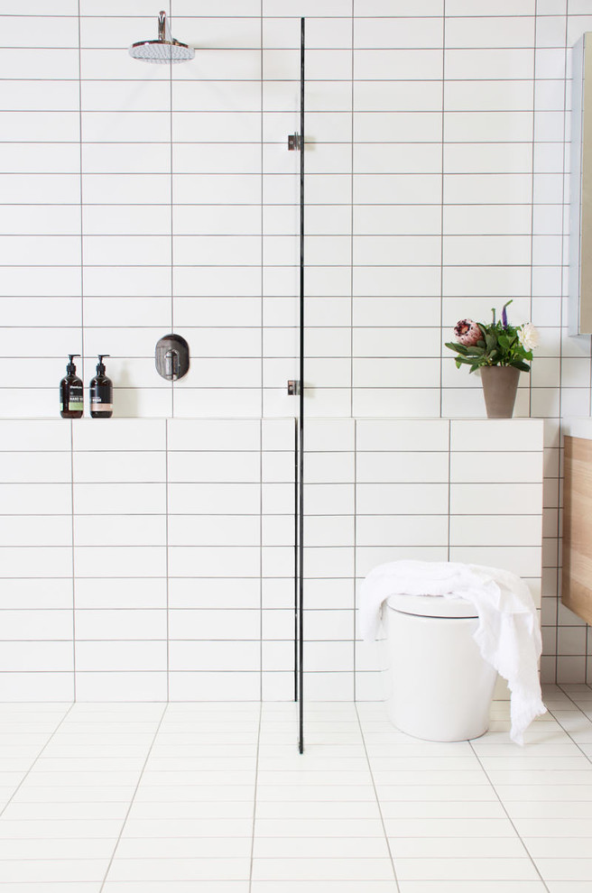 Photo of a mid-sized scandinavian 3/4 bathroom in Other with a two-piece toilet, white tile, subway tile, white walls, ceramic floors and a wall-mount sink.