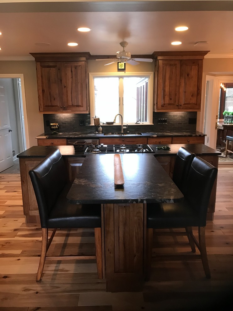 Inspiration for a large rustic l-shaped light wood floor and beige floor eat-in kitchen remodel with an undermount sink, raised-panel cabinets, medium tone wood cabinets, granite countertops, gray backsplash, ceramic backsplash, stainless steel appliances and an island