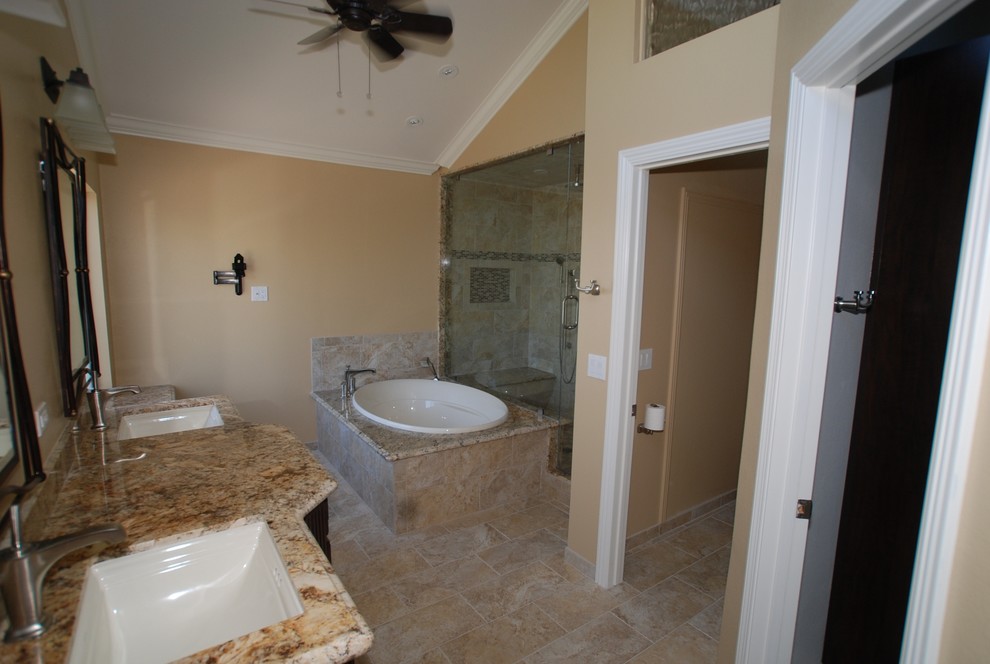 Photo of an expansive traditional master bathroom in Orange County with an undermount sink, raised-panel cabinets, distressed cabinets, granite benchtops, a drop-in tub, an alcove shower, a two-piece toilet, beige tile, porcelain tile, beige walls and porcelain floors.