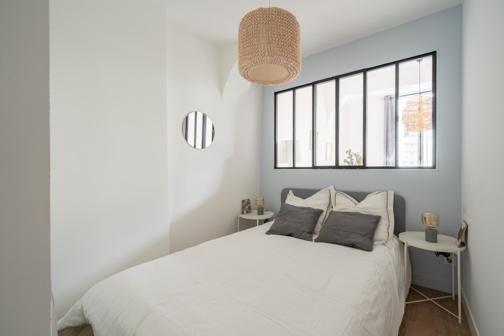 Aménagement d'une petite chambre grise et blanche contemporaine avec un mur bleu, un sol en bois brun, un sol marron, poutres apparentes et verrière.