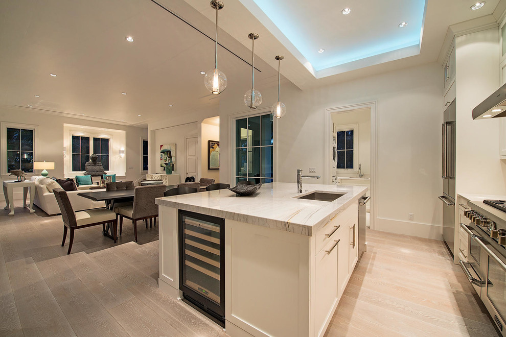 Inspiration for a mid-sized transitional u-shaped light wood floor open concept kitchen remodel in Miami with an undermount sink, recessed-panel cabinets, white cabinets, granite countertops, gray backsplash, stainless steel appliances and an island