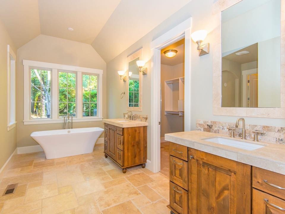 Design ideas for a mid-sized transitional master bathroom in Portland with furniture-like cabinets, medium wood cabinets, a freestanding tub, beige tile, stone tile, blue walls, travertine floors, an undermount sink, tile benchtops and beige floor.