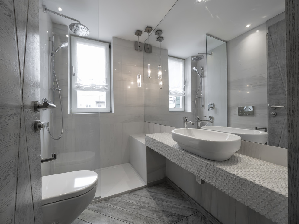Design ideas for a mid-sized modern bathroom in Los Angeles with open cabinets, a wall-mount toilet, grey walls, porcelain floors, a vessel sink, tile benchtops, grey floor and an open shower.