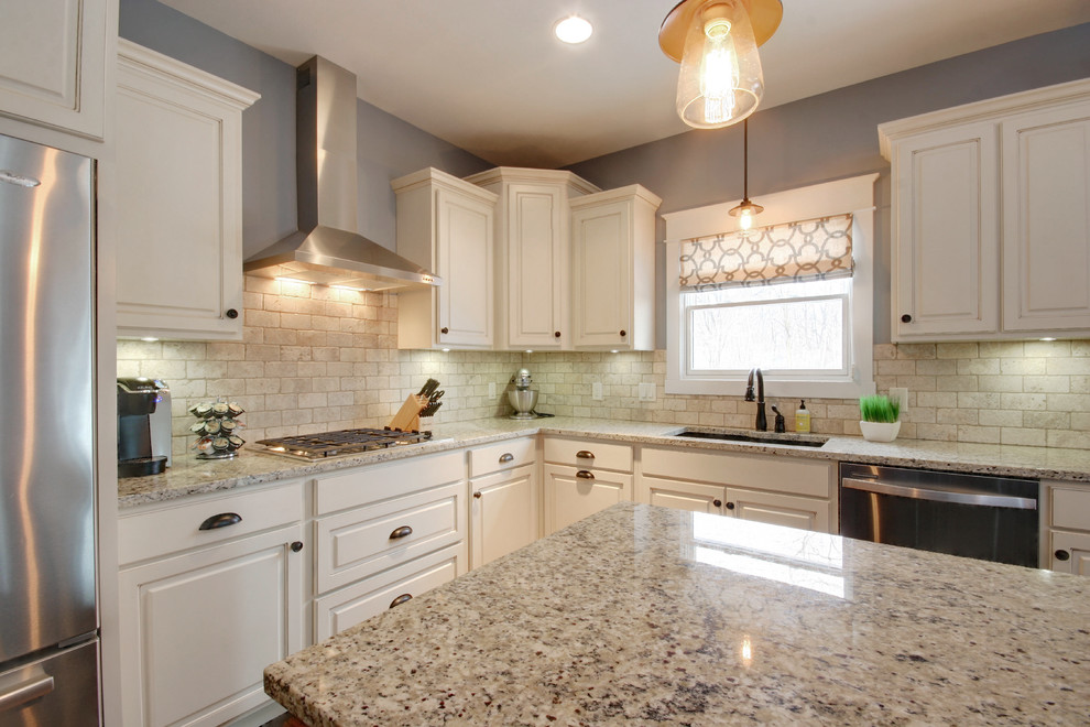 Photo of a large arts and crafts l-shaped eat-in kitchen in Grand Rapids with a drop-in sink, recessed-panel cabinets, white cabinets, granite benchtops, white splashback, ceramic splashback, stainless steel appliances, medium hardwood floors and with island.