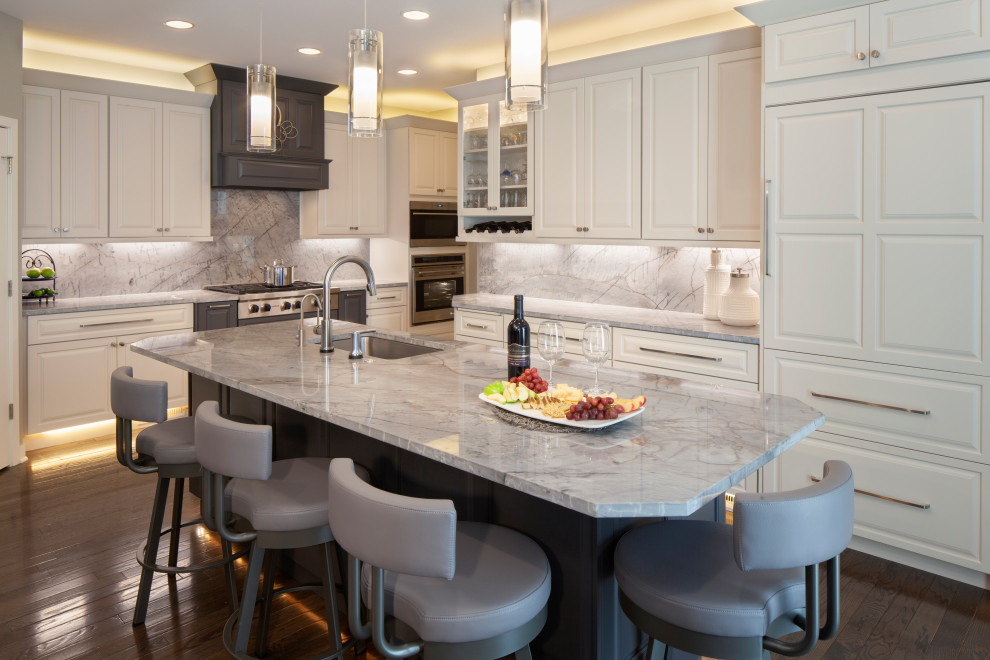 Inspiration for a transitional l-shaped dark wood floor and brown floor kitchen remodel with raised-panel cabinets, white cabinets, quartzite countertops, an island, an undermount sink, gray backsplash, paneled appliances and gray countertops
