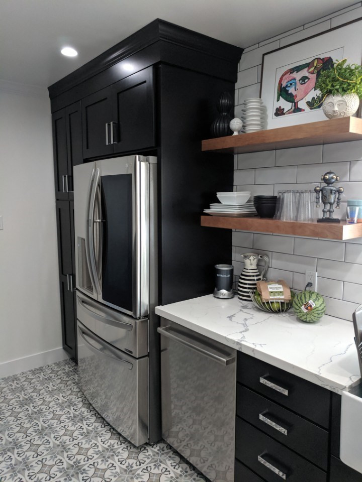 Photo of a mid-sized traditional galley separate kitchen in Phoenix with a farmhouse sink, flat-panel cabinets, black cabinets, quartzite benchtops, grey splashback, subway tile splashback, stainless steel appliances, ceramic floors, no island, grey floor and white benchtop.