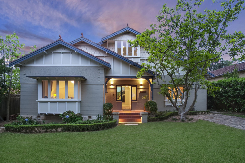 This is an example of a mid-sized traditional two-storey grey house exterior in Sydney with painted brick siding, a gable roof and a tile roof.