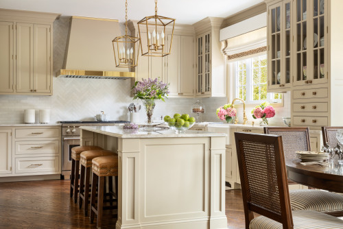 Elegant Canadian kitchen with cream-colored shaker cabinets, brass hardware, quartz countertops, and gold pendant lights — showcasing one of the best kitchen cabinet colors in Canada for 2025.