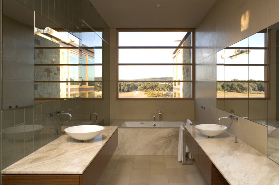 This is an example of a large contemporary master bathroom in Austin with an undermount tub, porcelain tile, beige walls, porcelain floors, a vessel sink, flat-panel cabinets, medium wood cabinets, gray tile and granite benchtops.