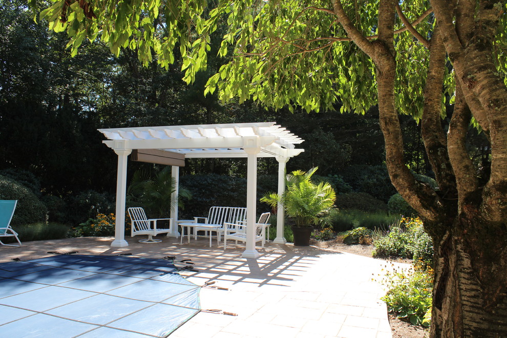 Medium sized classic back patio in Boston with a potted garden, natural stone paving and a pergola.