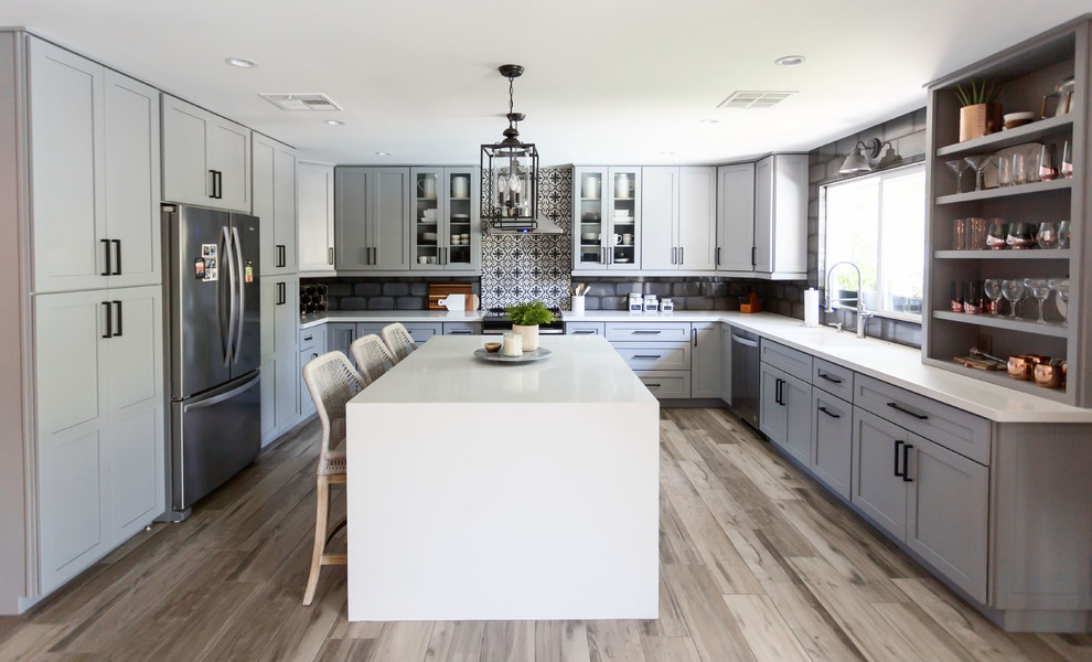 Example of a mid-sized transitional u-shaped light wood floor and gray floor eat-in kitchen design in Phoenix with an undermount sink, recessed-panel cabinets, gray cabinets, quartz countertops, multicolored backsplash, ceramic backsplash, stainless steel appliances, an island and white countertops