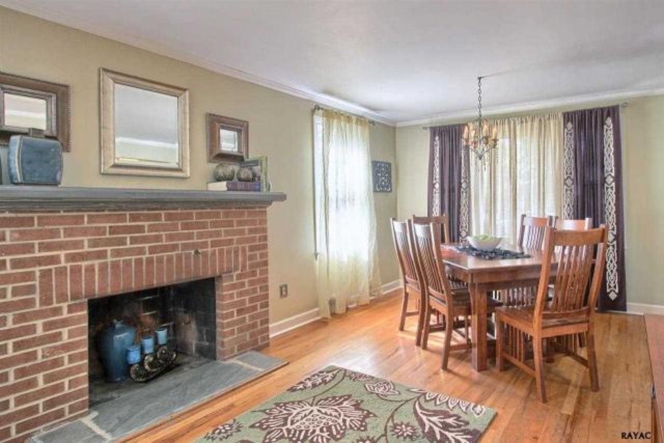 Photo of a small transitional separate dining room in Baltimore with beige walls, light hardwood floors, a standard fireplace and a brick fireplace surround.