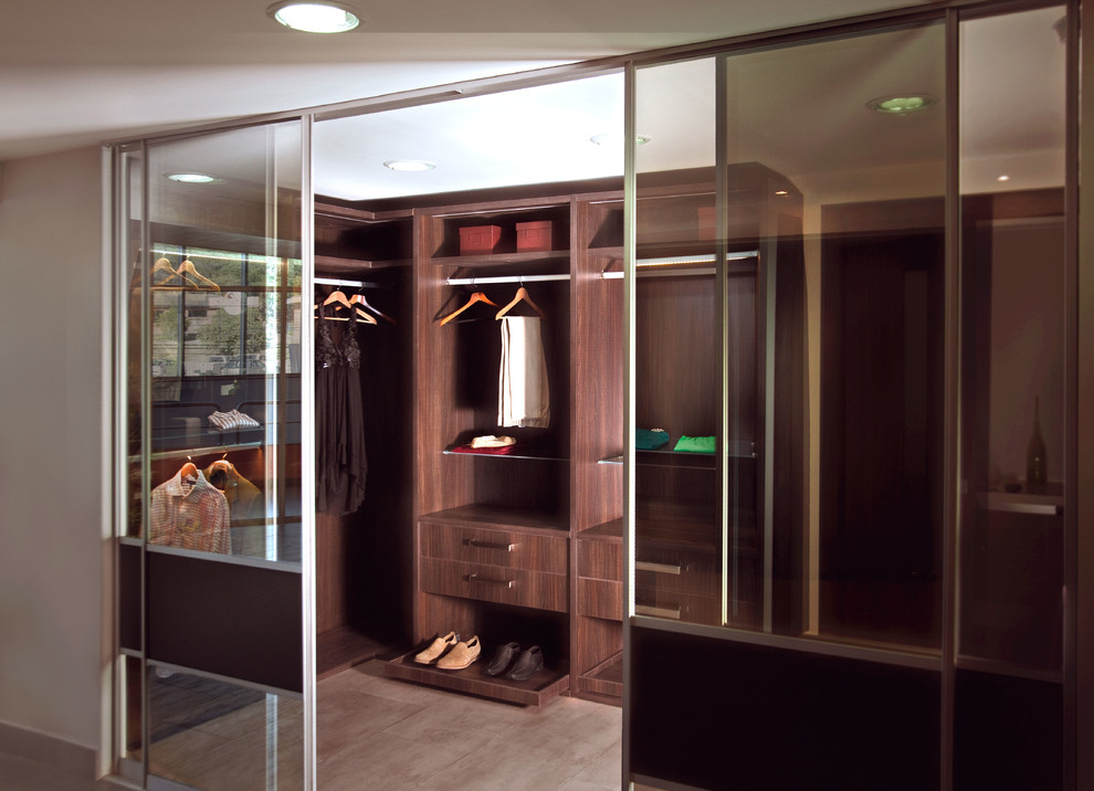 Photo of a mid-sized contemporary gender-neutral walk-in wardrobe in Houston with flat-panel cabinets, dark wood cabinets and ceramic floors.