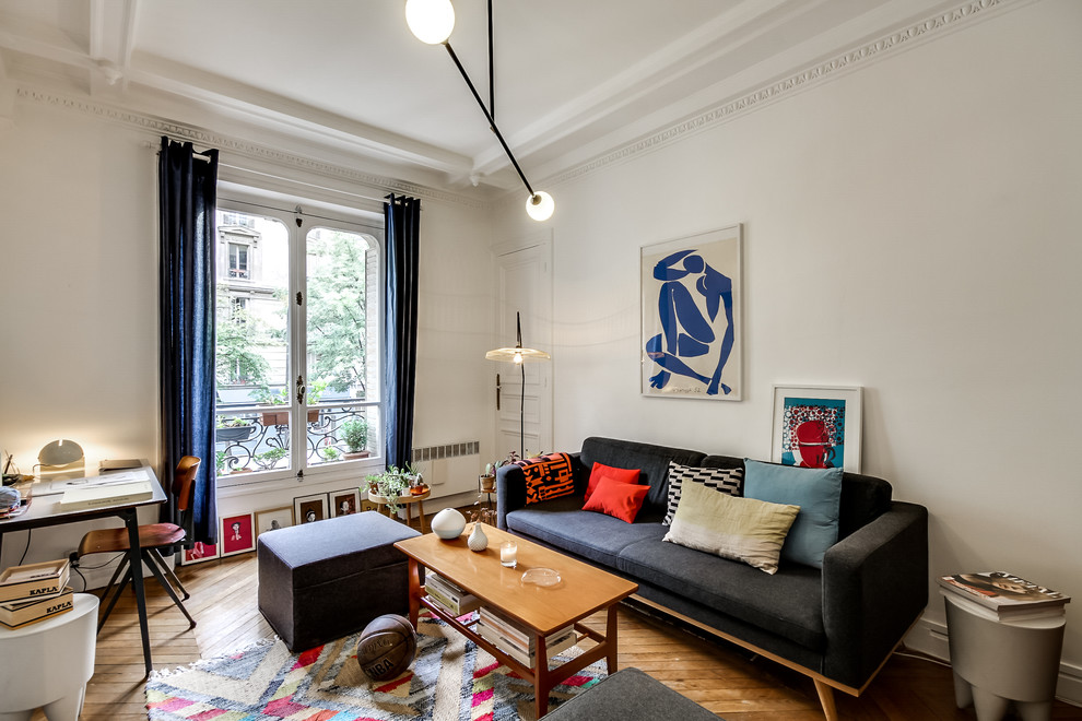 This is an example of a mid-sized transitional enclosed living room in Paris with white walls, medium hardwood floors, no fireplace, no tv and a library.