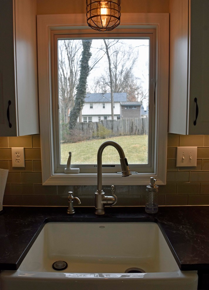Enclosed kitchen - mid-sized transitional galley laminate floor and brown floor enclosed kitchen idea in DC Metro with a farmhouse sink, shaker cabinets, white cabinets, granite countertops, gray backsplash, subway tile backsplash, stainless steel appliances, no island and black countertops