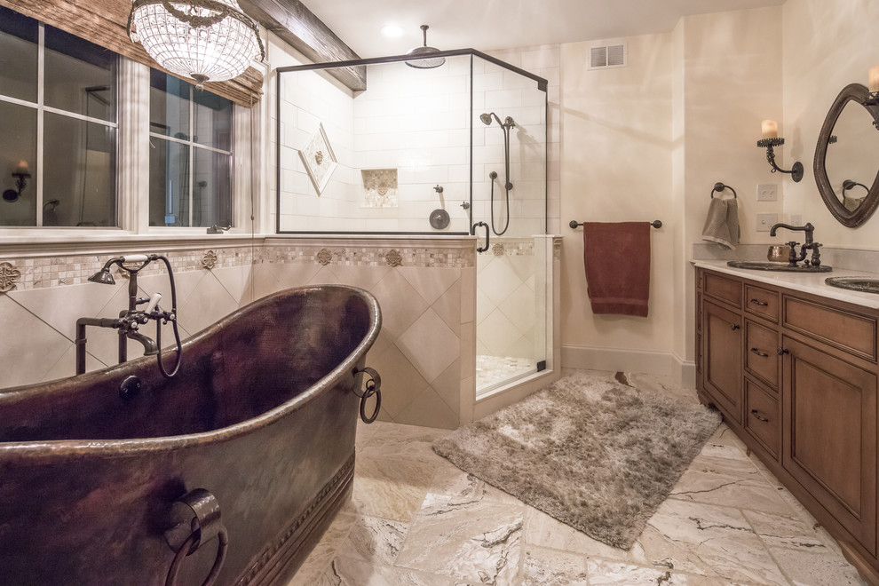 Photo of a large country master bathroom in Boston with furniture-like cabinets, medium wood cabinets, a freestanding tub, a corner shower, a two-piece toilet, beige tile, marble, black walls, marble floors, a drop-in sink, granite benchtops, beige floor and a hinged shower door.