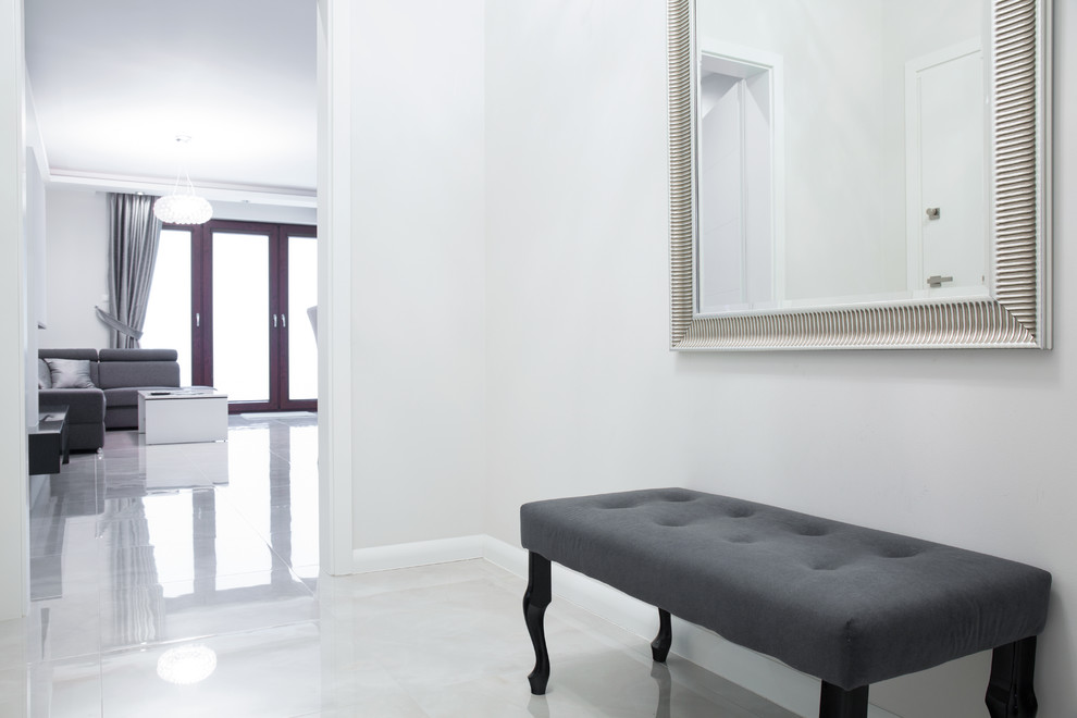 This is an example of a contemporary entry hall in Melbourne with white walls, porcelain floors and beige floor.