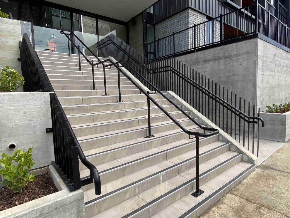 Foto de escalera recta moderna de tamaño medio con escalones de hormigón, contrahuellas de hormigón y barandilla de metal