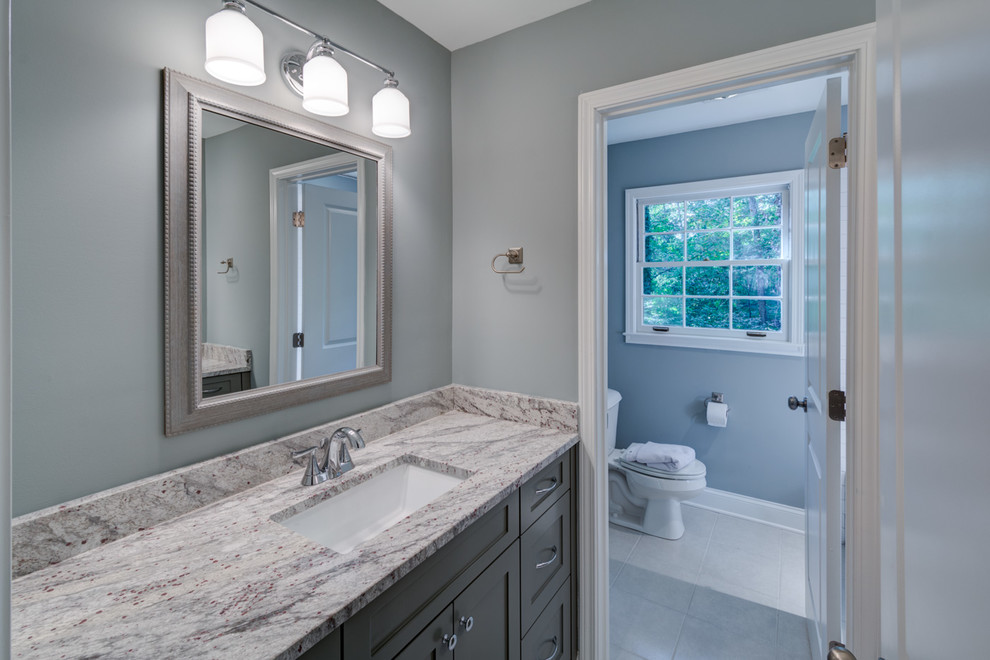 Inspiration for a mid-sized transitional kids bathroom in Atlanta with shaker cabinets, grey cabinets, an alcove tub, a shower/bathtub combo, a one-piece toilet, gray tile, grey walls, ceramic floors, an undermount sink, granite benchtops, grey floor and a shower curtain.