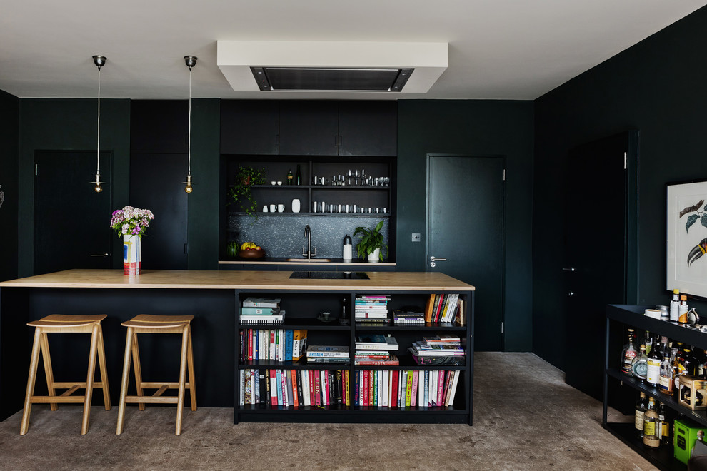Inspiration for a mid-sized transitional kitchen in London with flat-panel cabinets, black cabinets, wood benchtops, black splashback, concrete floors, with island, grey floor and a single-bowl sink.