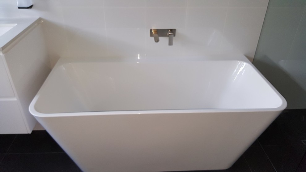 Large contemporary wet room bathroom in Brisbane with white cabinets, a freestanding tub, a wall-mount toilet, white tile, white walls, cement tiles, an undermount sink, engineered quartz benchtops and an open shower.