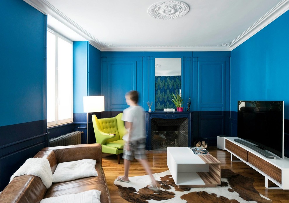 На фото: открытая гостиная комната среднего размера:: освещение в стиле неоклассика (современная классика) с синими стенами, светлым паркетным полом, стандартным камином, фасадом камина из камня, бежевым полом, деревянным потолком и обоями на стенах с