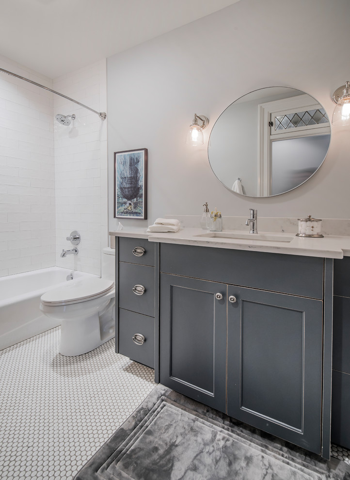 Inspiration for a transitional bathroom in Columbus with recessed-panel cabinets, grey cabinets, a drop-in tub, a shower/bathtub combo, a one-piece toilet, white tile, subway tile, grey walls, mosaic tile floors, an undermount sink, marble benchtops, white floor and a shower curtain.