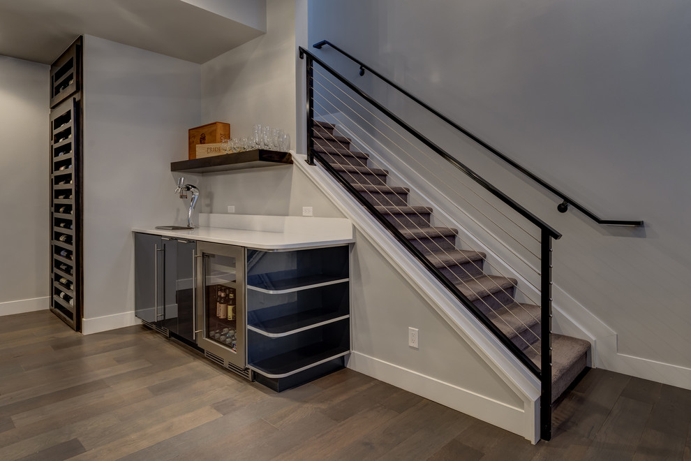 This is an example of a large transitional look-out basement in Denver with grey walls, medium hardwood floors, no fireplace and beige floor.