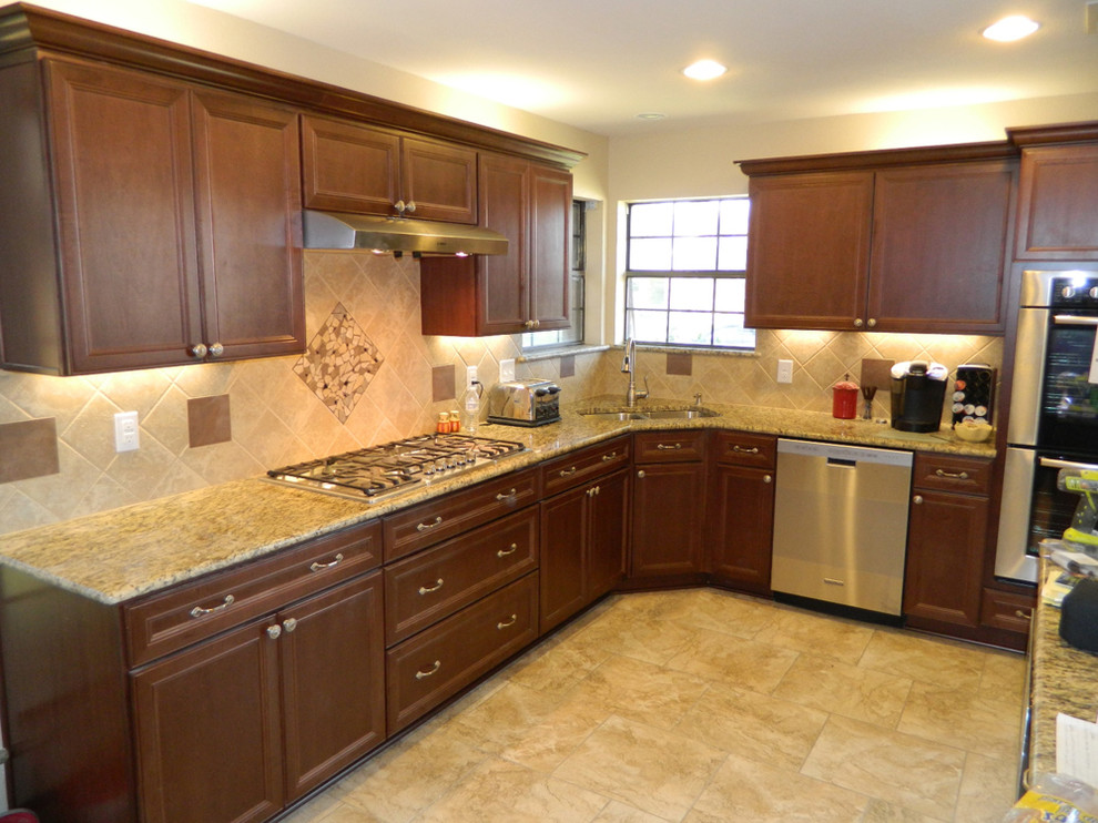 Photo of a mid-sized traditional l-shaped separate kitchen in Dallas with an undermount sink, recessed-panel cabinets, dark wood cabinets, granite benchtops, brown splashback, ceramic splashback, stainless steel appliances, ceramic floors, no island, beige floor and brown benchtop.