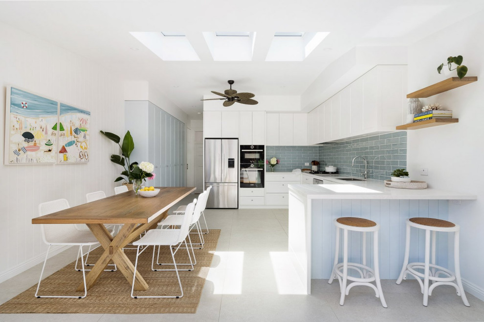 Design ideas for a large beach style u-shaped eat-in kitchen in Sydney with a drop-in sink, shaker cabinets, white cabinets, quartz benchtops, blue splashback, subway tile splashback, stainless steel appliances, porcelain floors, no island, grey floor and white benchtop.