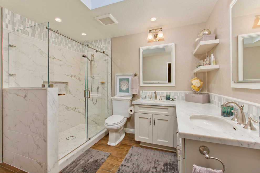 This is an example of a large traditional master bathroom in San Diego with shaker cabinets, white cabinets, a corner shower, a two-piece toilet, white tile, porcelain tile, ceramic floors, an undermount sink, marble benchtops and grey walls.
