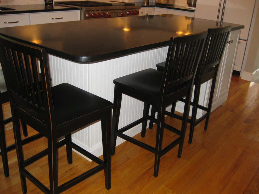 Eat-in kitchen - transitional u-shaped medium tone wood floor eat-in kitchen idea in Boston with an undermount sink, recessed-panel cabinets, white cabinets, gray backsplash, subway tile backsplash, stainless steel appliances, an island and black countertops