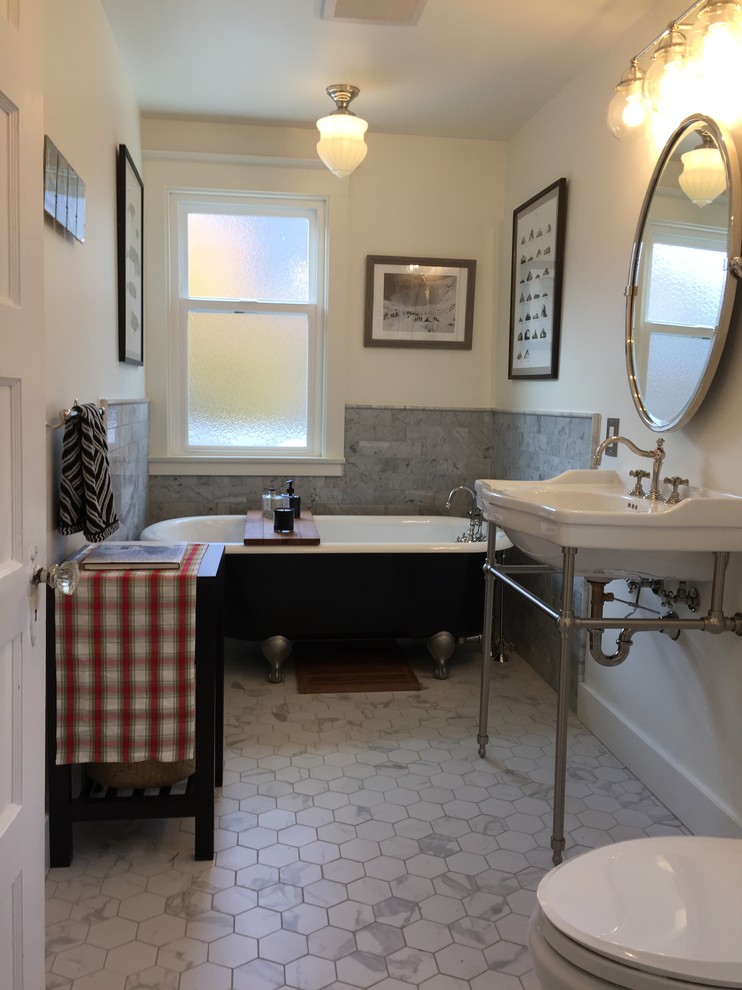 This is an example of a mid-sized transitional 3/4 bathroom in Seattle with a claw-foot tub, a two-piece toilet, white tile, marble floors and a pedestal sink.