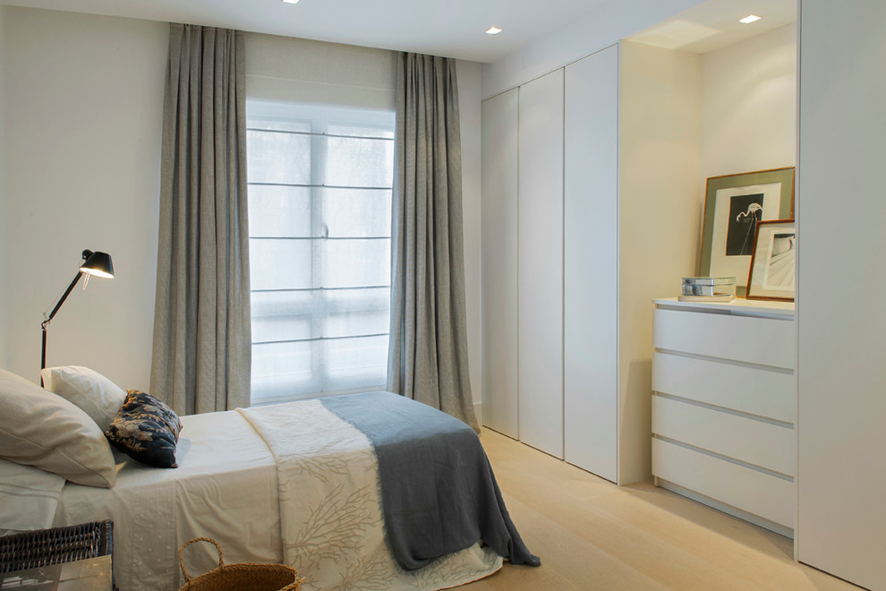 Design ideas for a mid-sized scandinavian master bedroom in Madrid with white walls, light hardwood floors and no fireplace.