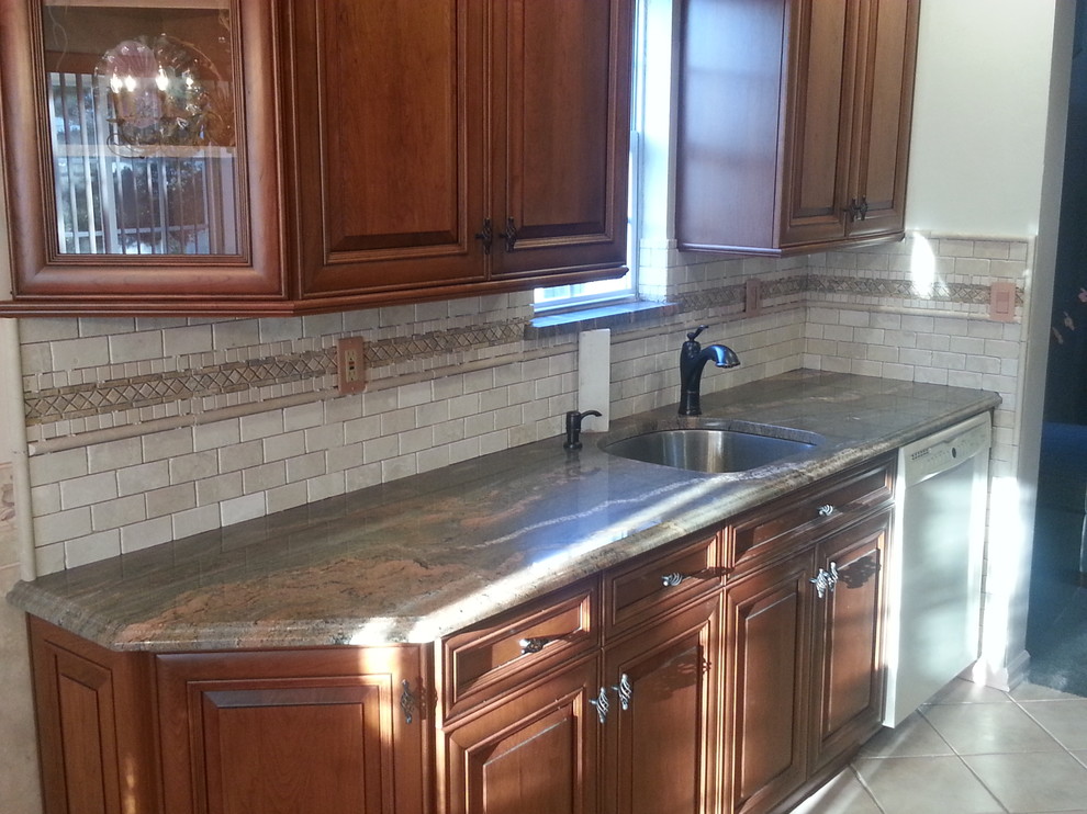 Eat-in kitchen - mid-sized l-shaped light wood floor eat-in kitchen idea in Newark with a drop-in sink, raised-panel cabinets, white cabinets, granite countertops, white backsplash, subway tile backsplash, stainless steel appliances and an island