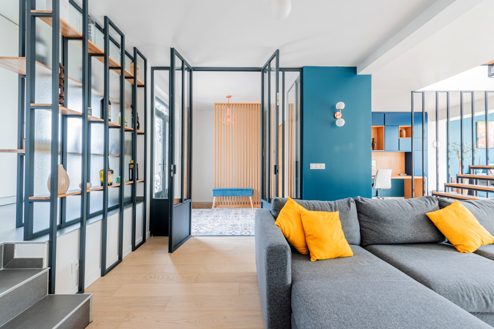 Réalisation d'une grande salle de séjour urbaine ouverte avec une bibliothèque ou un coin lecture, un mur bleu, parquet clair, un poêle à bois, un sol beige et un téléviseur indépendant.