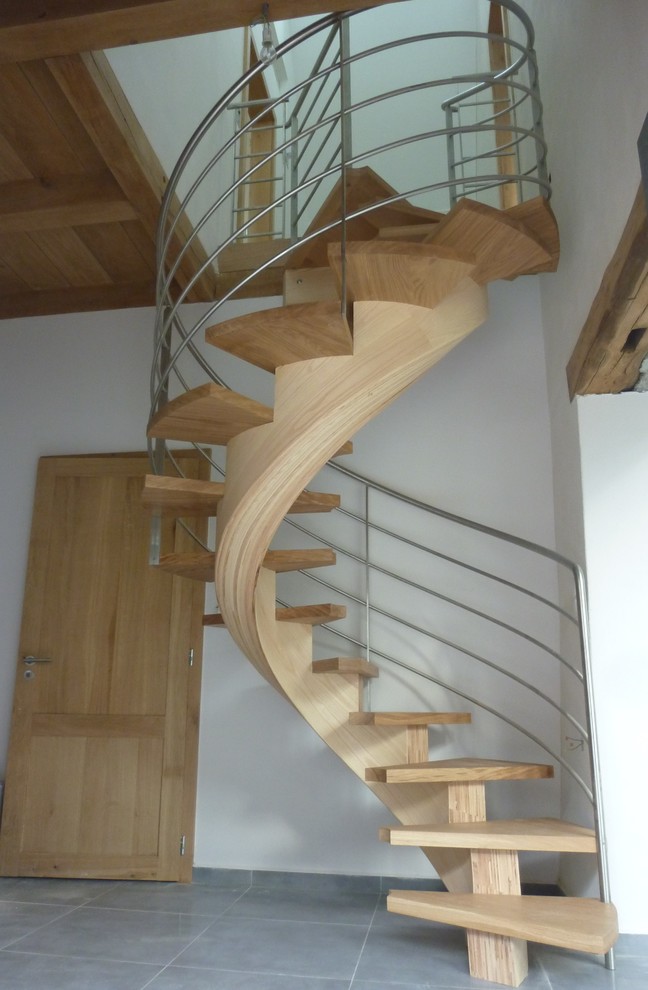 This is an example of a contemporary wood spiral staircase in Lyon with metal railing.