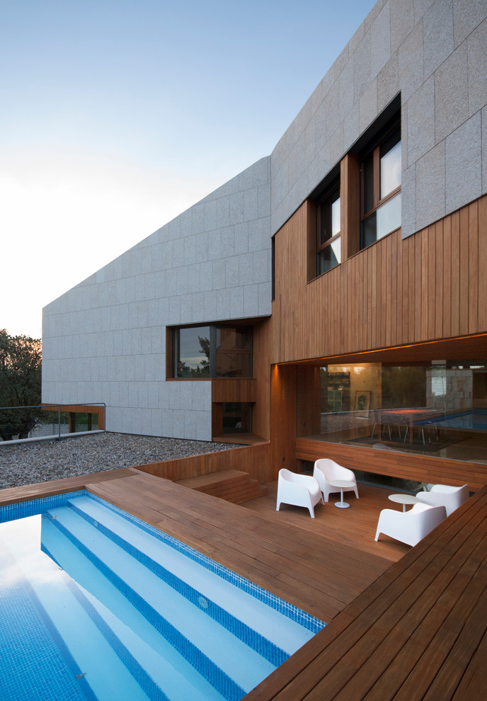 Expansive contemporary backyard deck in Madrid with a water feature and no cover.