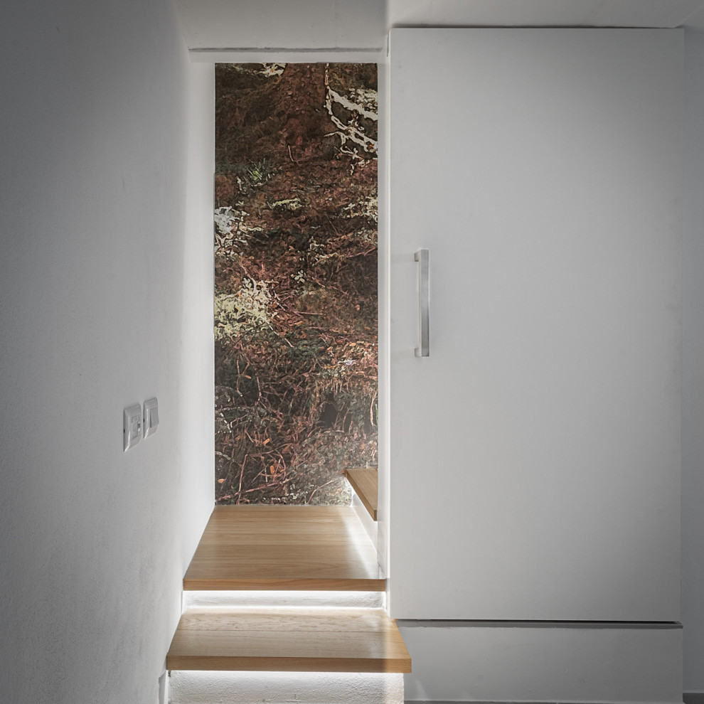 На фото: маленькая угловая бетонная лестница в современном стиле с деревянными ступенями и обоями на стенах для на участке и в саду
