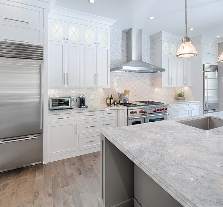 Inspiration for a mid-sized transitional single-wall open plan kitchen in Boston with an undermount sink, recessed-panel cabinets, white cabinets, marble benchtops, white splashback, stone tile splashback, stainless steel appliances, dark hardwood floors, with island and brown floor.