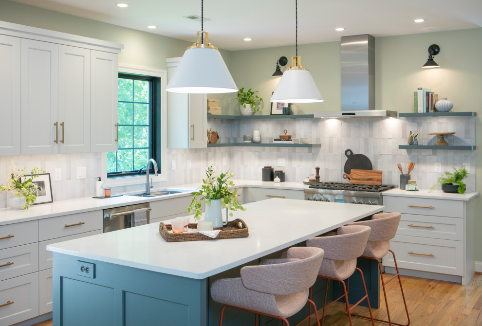 Kitchen - transitional l-shaped medium tone wood floor kitchen idea with a double-bowl sink, shaker cabinets, white cabinets, multicolored backsplash, stainless steel appliances, an island and white countertops